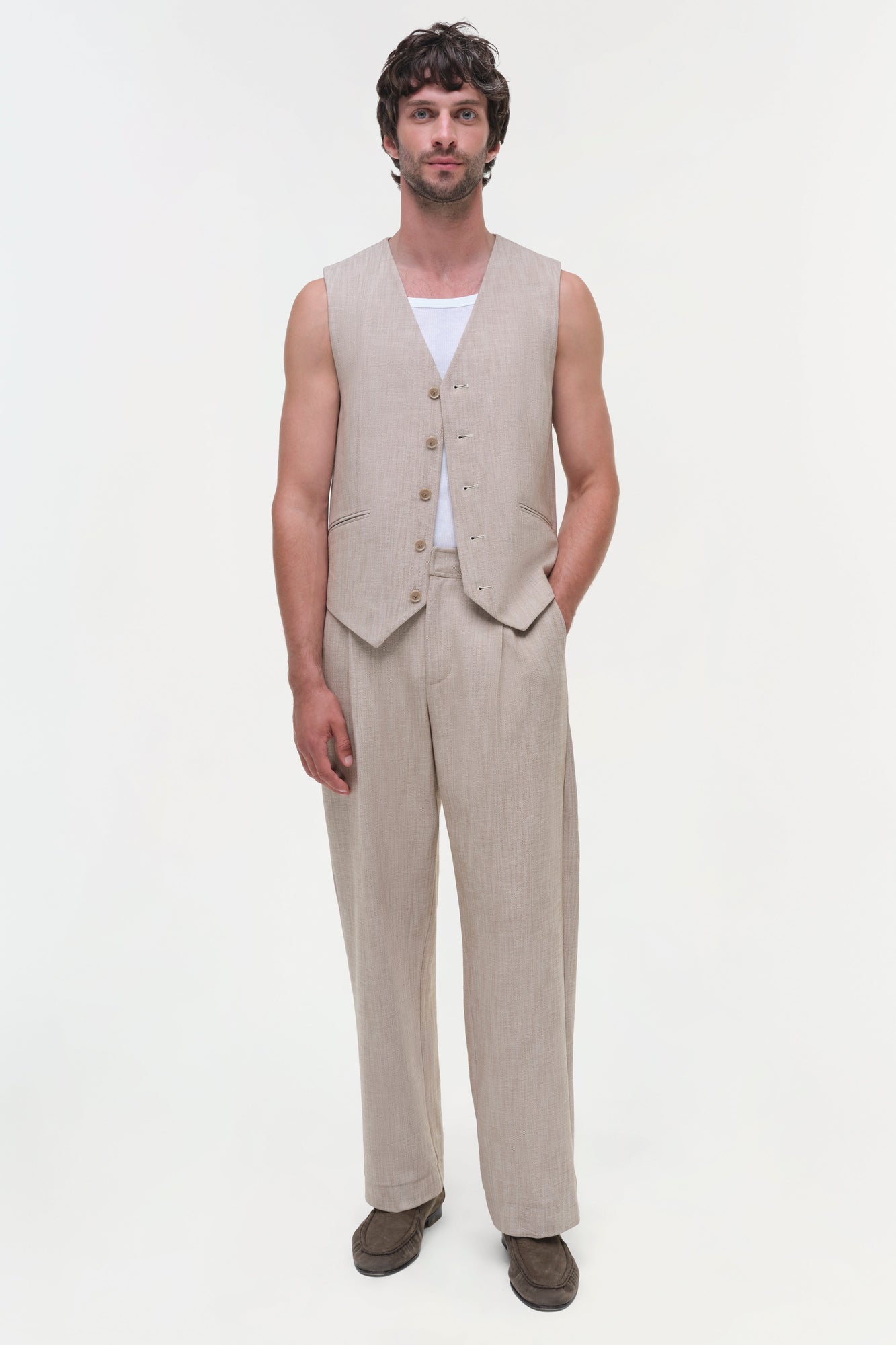 Beige textured vest with button front and matching trousers, worn over white undershirt.