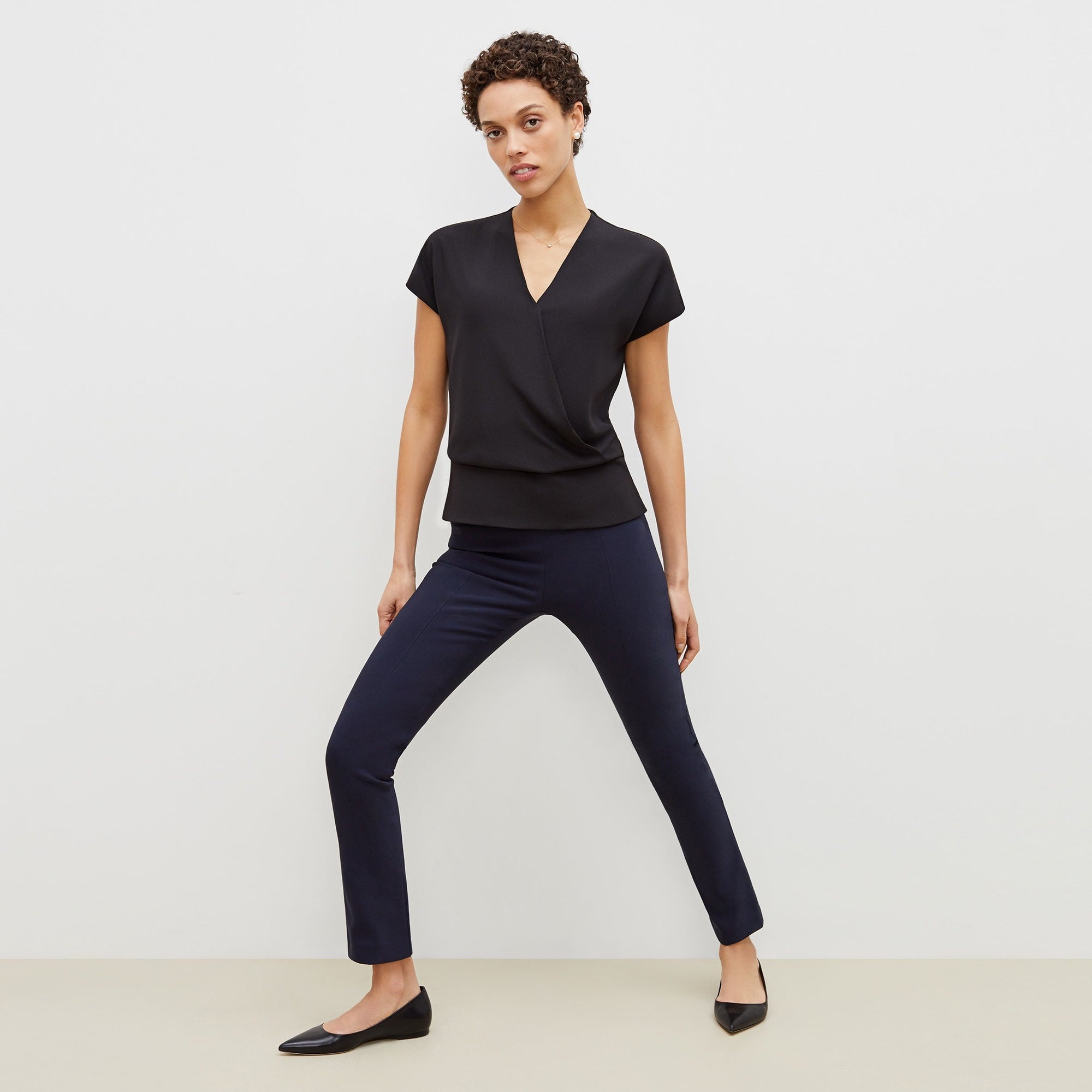 Front image of a woman standing wearing the foster pant in dark navy