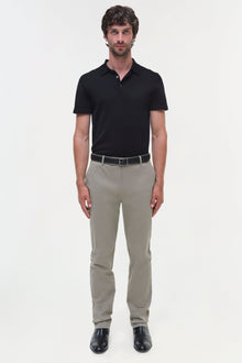 Man wearing black polo shirt and beige cotton twill trousers with belt and black shoes.