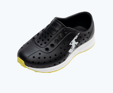 Angled view of a Native Shoes Kids Robbie Sugarlite Glow Kids | Jiffy Black/ Shell White/ Shell Lightning Glow/ Pickle Speckle Rubber Footwear