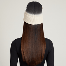 Back view of model wearing a black and white ombre beanie with long brown hair on a plain background