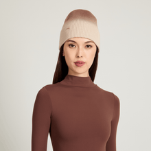 Model wearing a beige knit ombre beanie against a light gray background