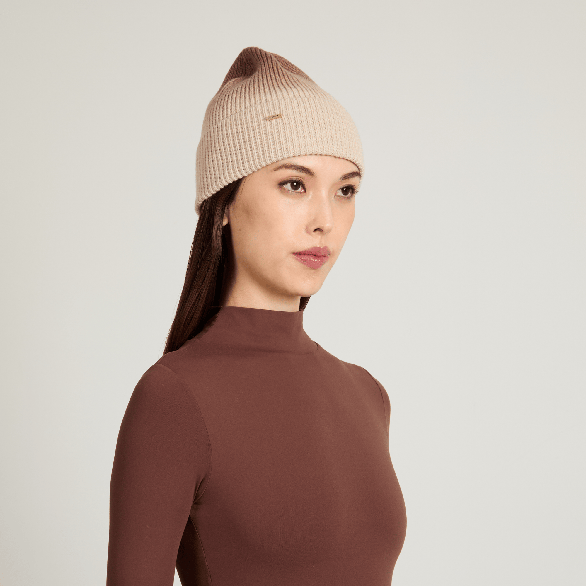 Model wearing a beige knit ombre beanie against a light background