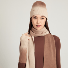 Model wearing a beige knit ombre hat, scarf and gloves on a light gray background