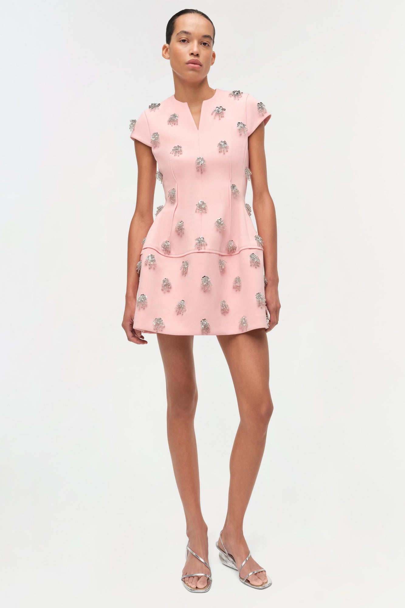 Pink mini dress with silver beaded embellishments, short sleeves, and a tiered skirt design.
