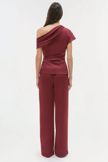 Burgundy draped satin top with one-shoulder neckline and ruched waist detail, shown on model from back.
