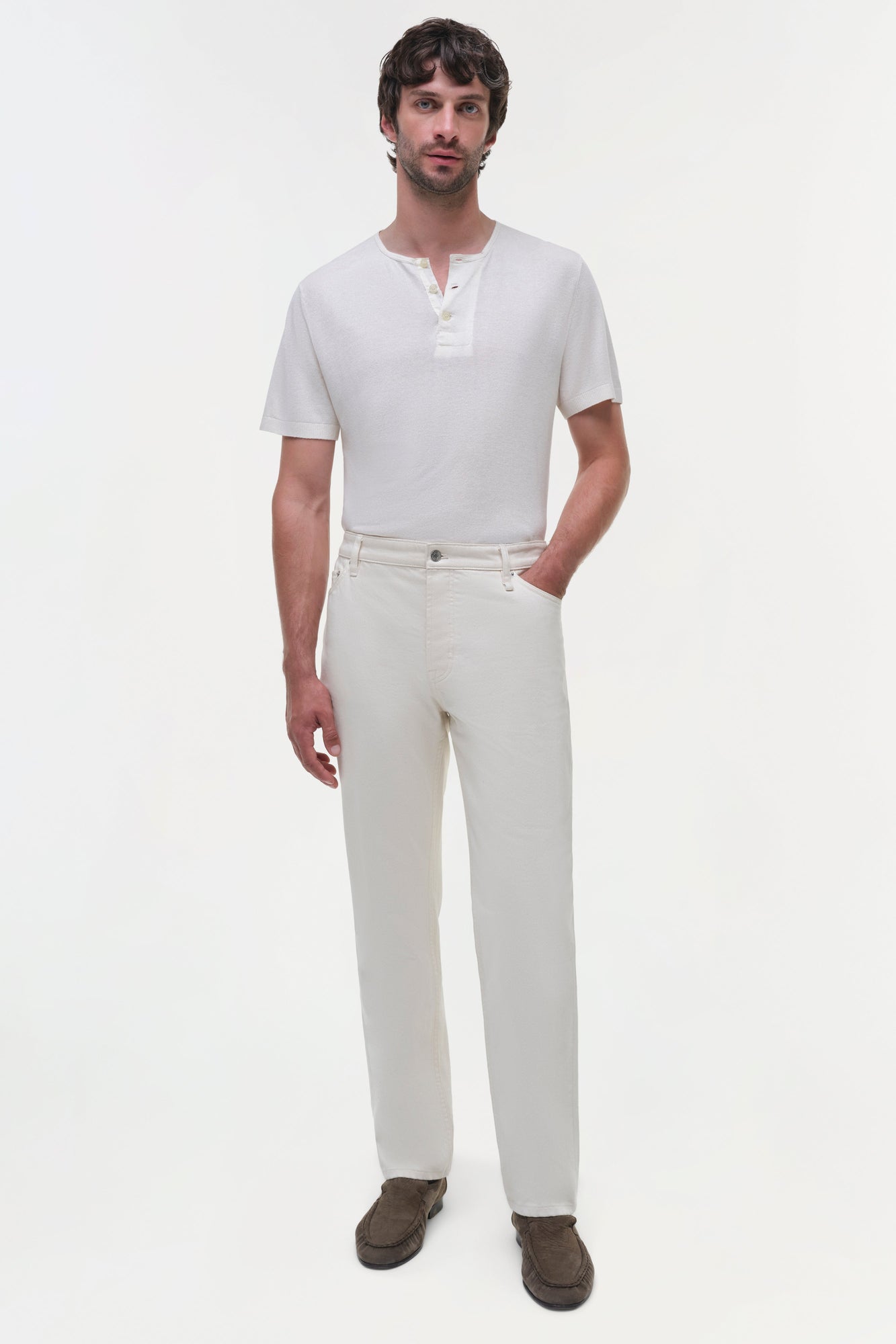 Man wearing cream wide-leg jeans with white henley shirt and brown suede loafers.