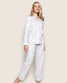 A woman in Petite Plumes Womens Flannel Pajama Set in Apres Ski smiles while standing. The collared top has buttons, and the full-length pants promise comfort in brushed cotton flannel. Her long blonde hair cascades against a plain background, enhancing the serene scene.