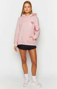 Close-up of the pink hoodie showing the red heart graphic on the chest and ribbed sleeve cuffs