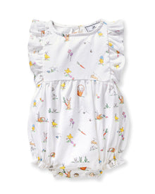 A young child with brown hair in pigtails wears the Baby's Twill Ruffled Romper in Easter Frolic, featuring colorful animal and floral prints, standing against a plain light background.
