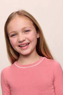 Model wearing Kids TENCEL Modal Unisex Long PJ Set in Sunkissed Coral/Ivory