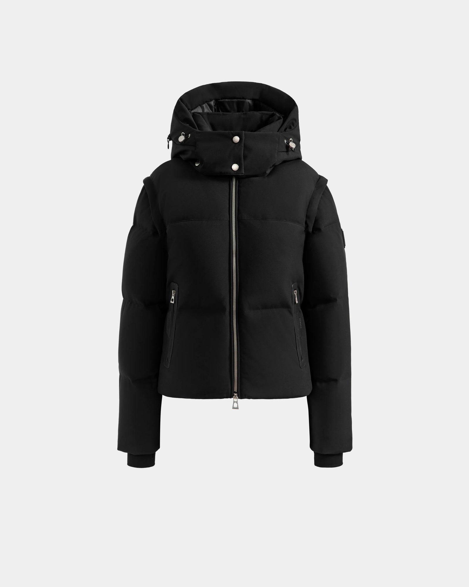 The DELILAH M - L125538 Black by Rudsak is a women's black hooded down puffer jacket with a front zipper, side zip pockets, and button details on the hood, shown against a plain light gray background.