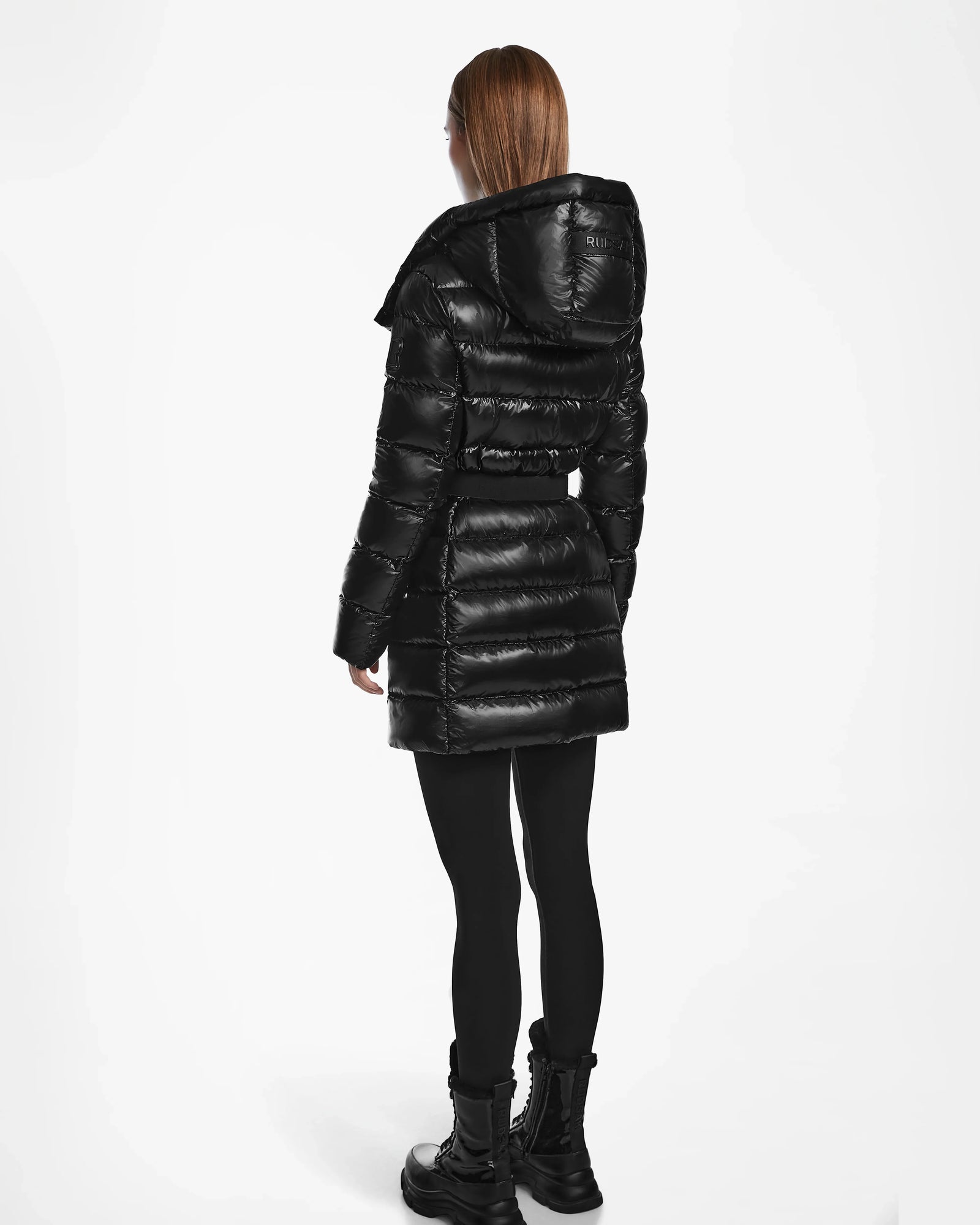 A woman wears the Rudsak FRIDA S - L124526 Black, a black quilted down jacket with a removable hood.