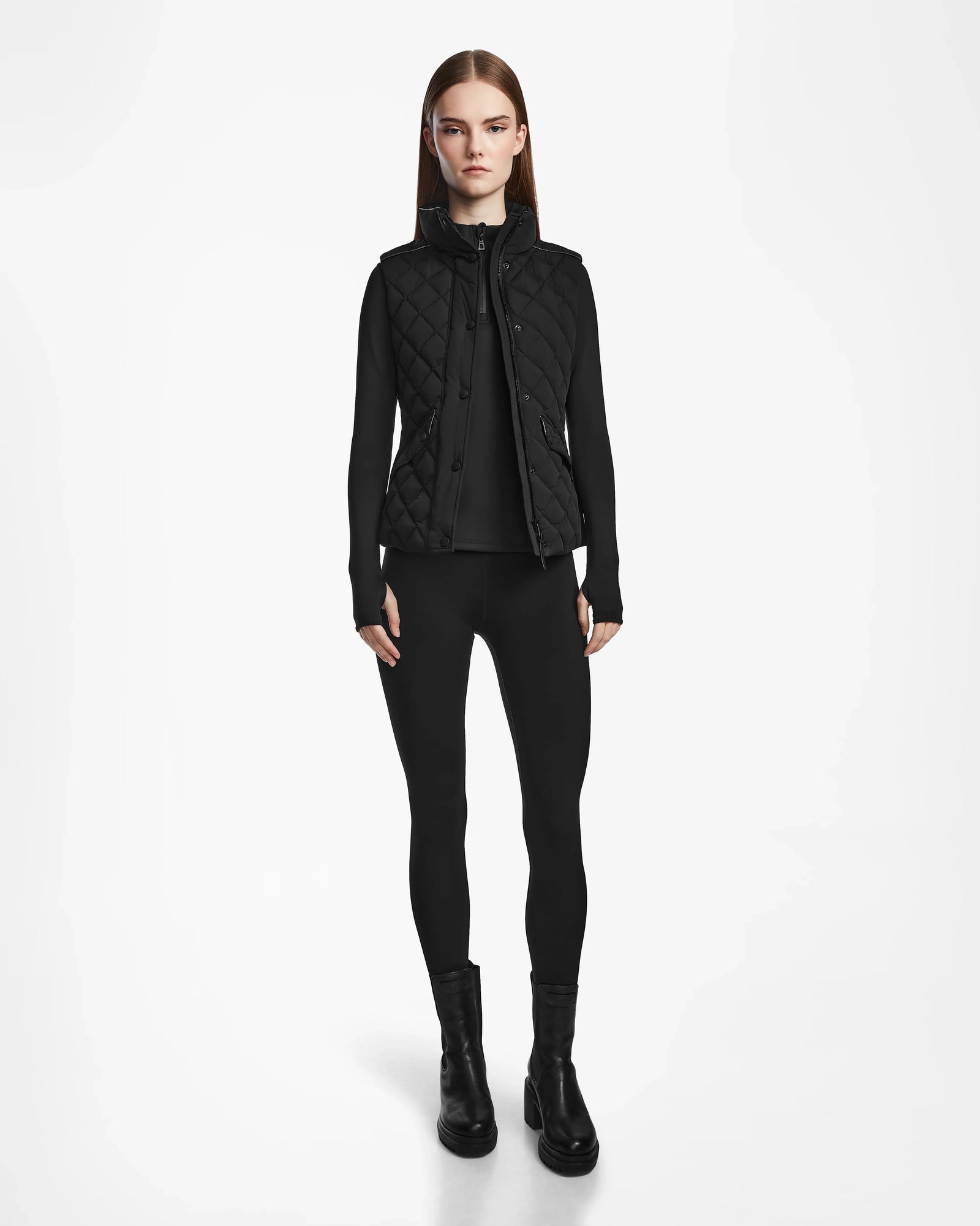 A woman wearing the Rudsak MATILDA - L124504 Black vest layers it stylishly over black clothing, making it perfect for transitional weather.