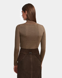 A woman with straight brown hair is shown from the back, wearing the Rudsak SIMONA S - 8424523 Espresso long-sleeve turtleneck top and dark brown skirt with adjustable waist belt, set against a plain white background.