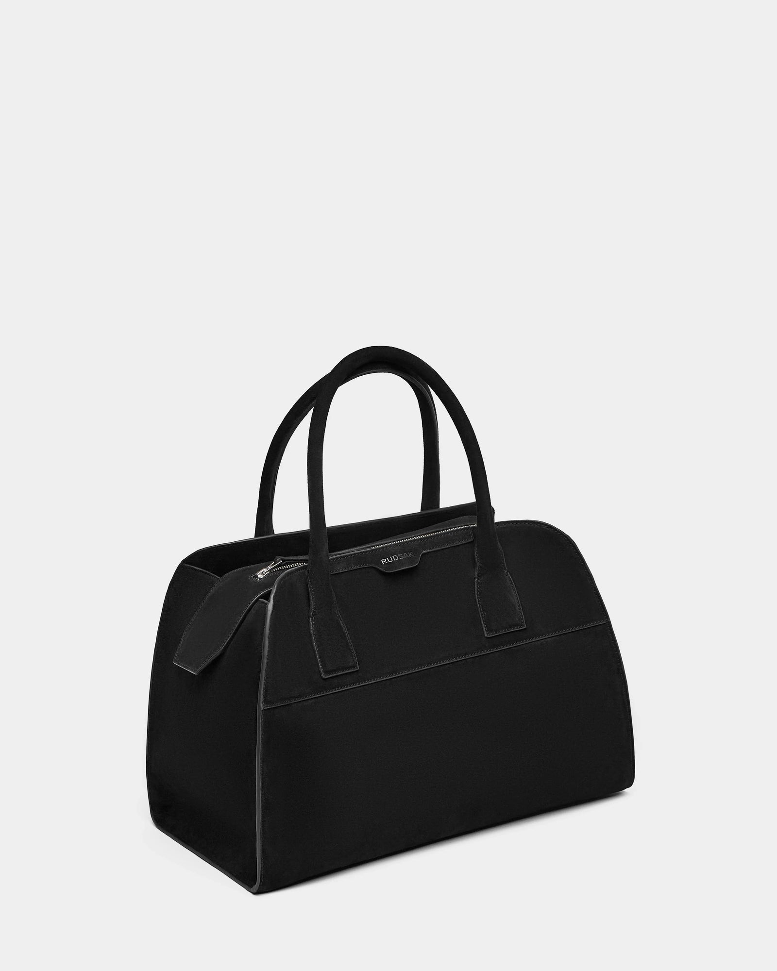 The Rudsak YASMINA L CS - 8324524 Black is a women’s large tote bag with two handles and a zipper closure, featuring a minimalist, structured design ideal for everyday style. Displayed against a plain light gray background.