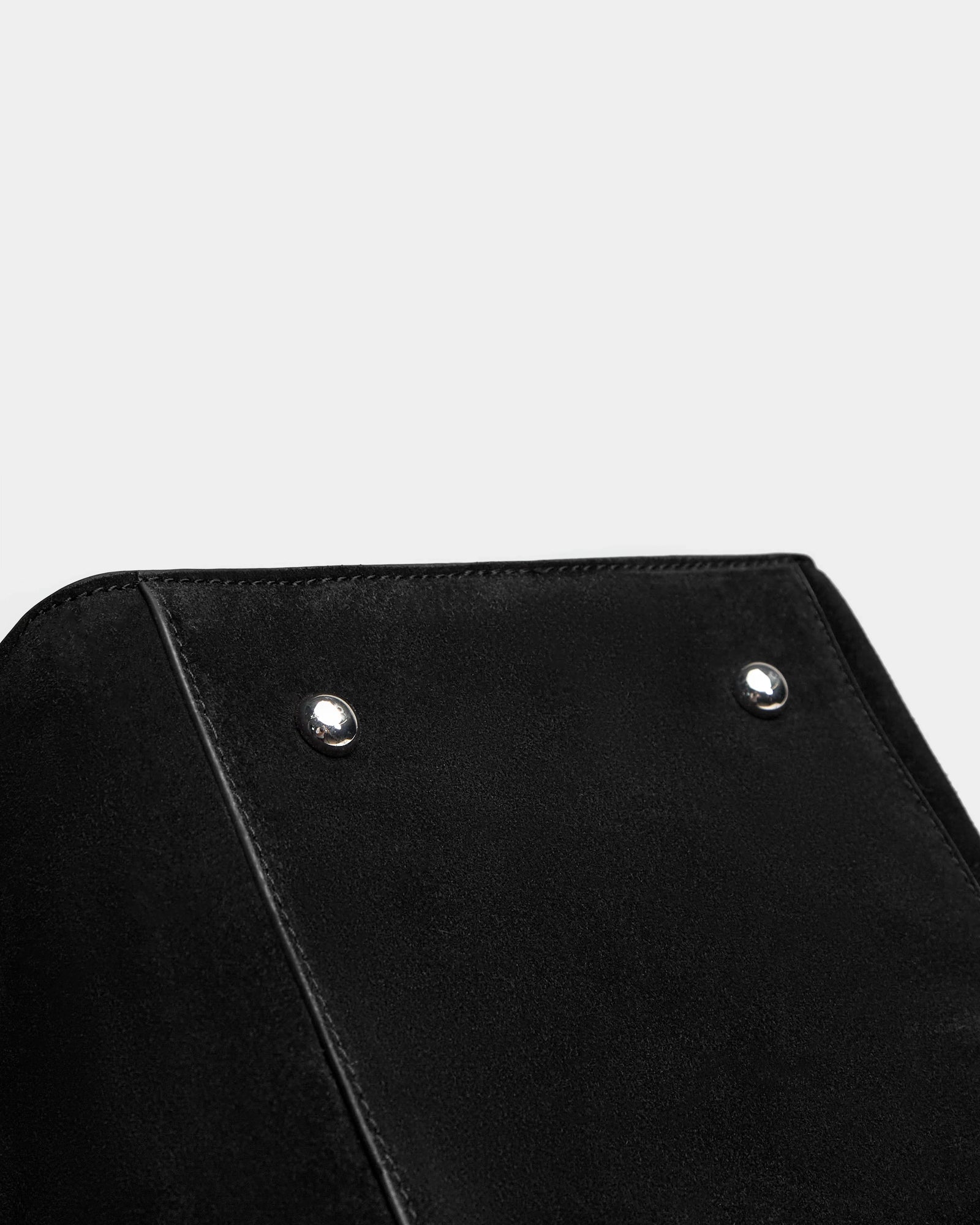 Close-up of the top corner of a Rudsak YASMINA L CS - 8324524 Black womens large suede tote, showing two silver metal studs, against a plain light gray background.