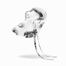 Clear glass sculpture with black floral patterns on a white background