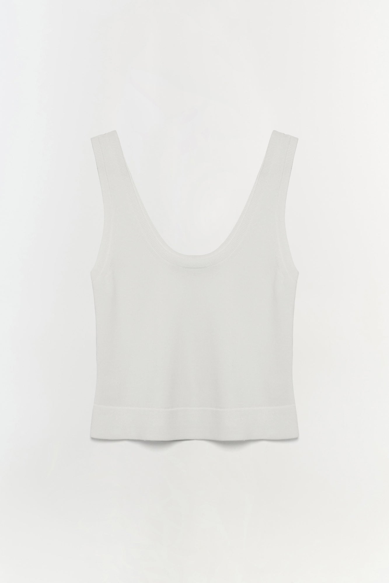 White sleeveless tank top with a scoop neckline and ribbed trim at the hem.
