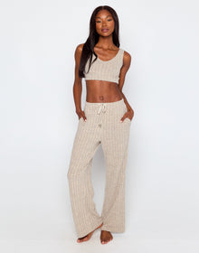 Woman wearing a beige ribbed knit loungewear set, featuring a cropped tank top with a scoop neckline and wide-leg drawstring pants with side pockets, standing barefoot against a plain white background.