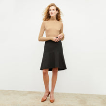 Front image of a woman standing wearing the axam top in camel