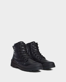 The ARTUR - M223501 Black men's boots by Rudsak feature stylish black weather-treated leather, rugged soles, side zippers, and padded collars, shown against a plain light grey background.