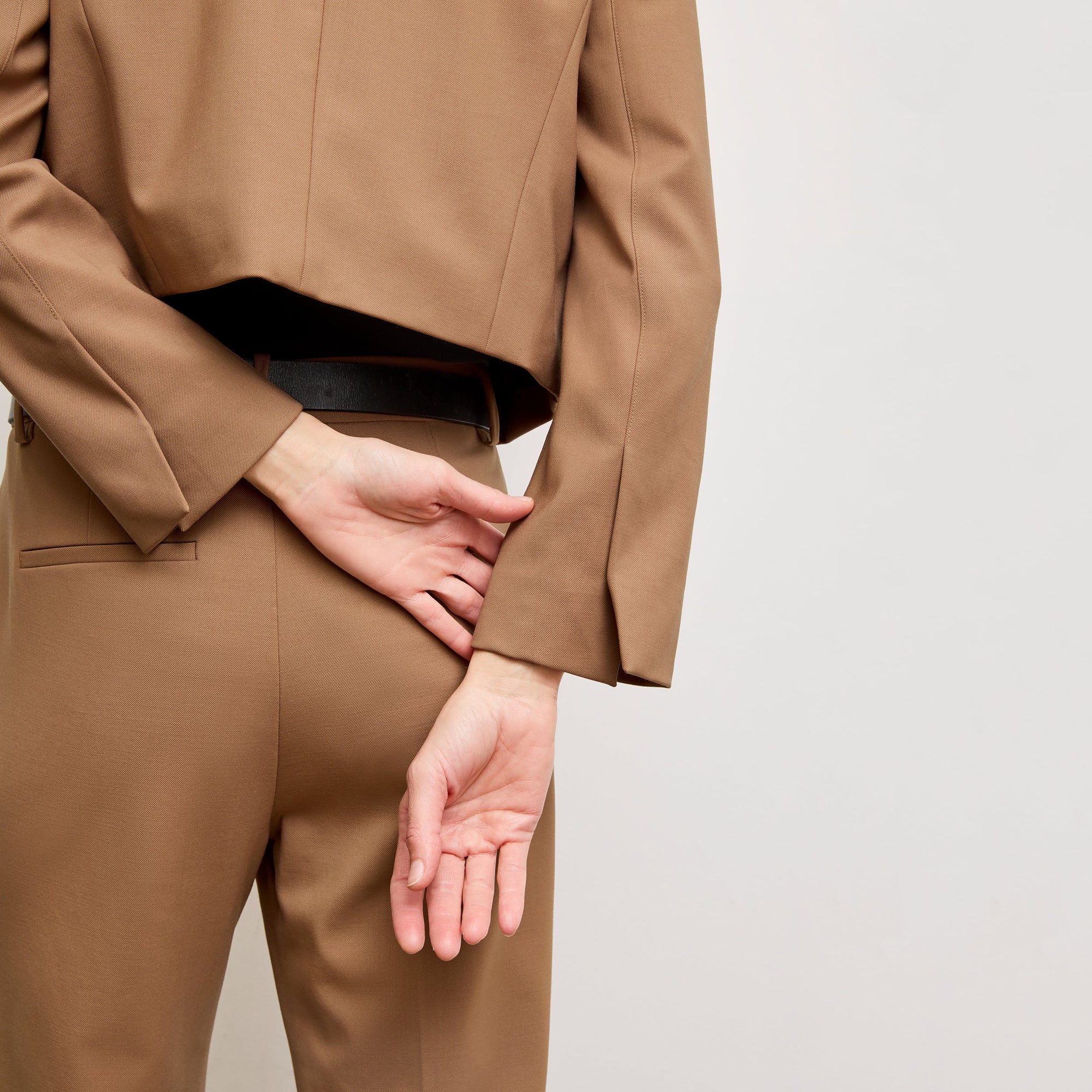 back image of a woman standing wearing the Neale jacket in camel