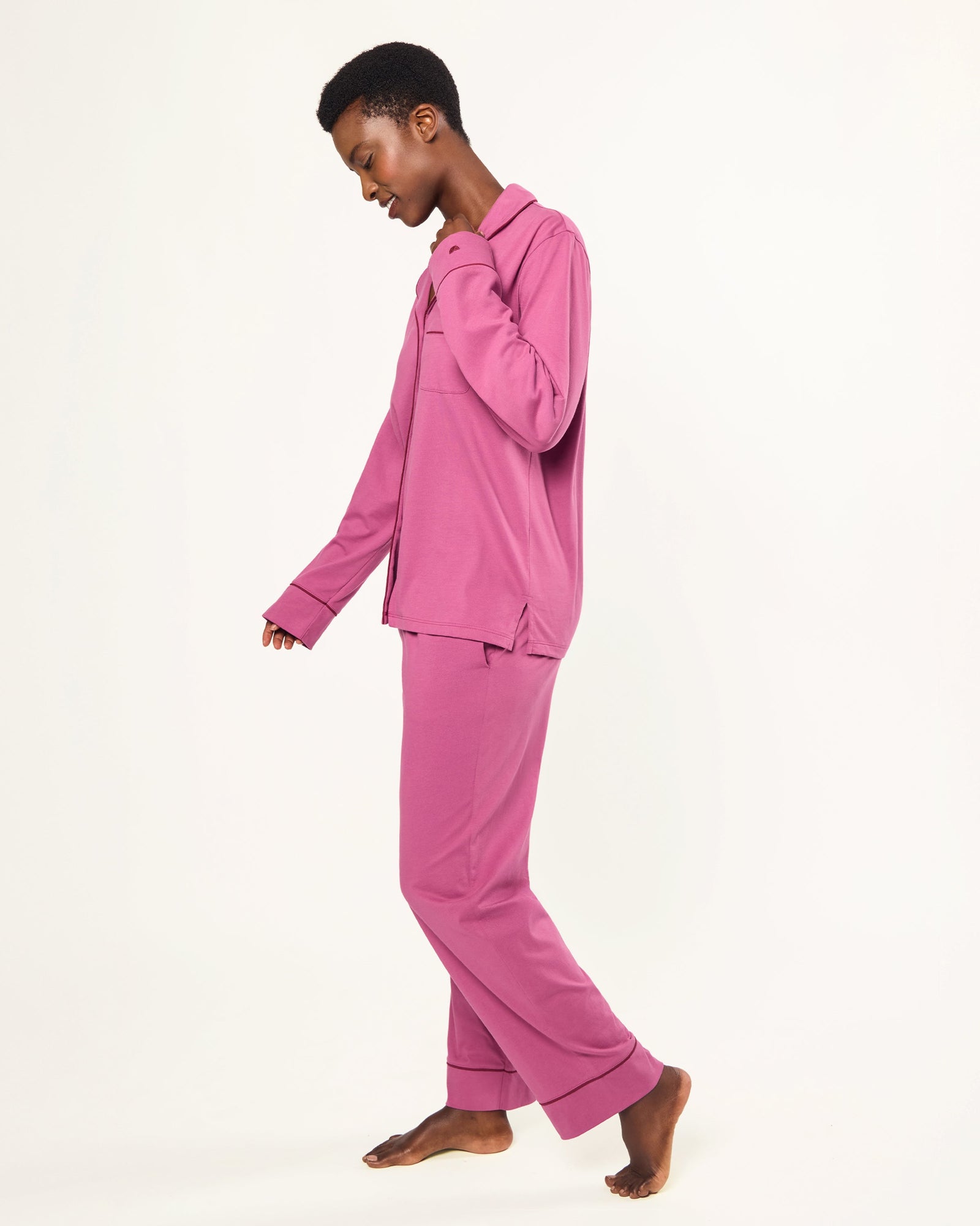 The Women's Pima Pajama Set in Rosewood, featuring a long-sleeve button-up top with a collar and chest pocket, and elastic-waist pants, is shown laid flat on a white background.