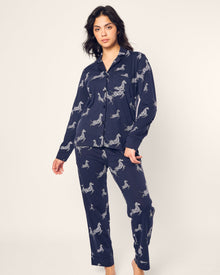 Against a plain backdrop, someone is dressed in the Petite Plume Womens Pima Pajama Set in Zebre de Nuit, featuring a luxury zebra print in navy and crafted from soft Peruvian Pima cotton.