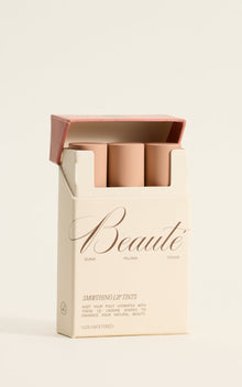 Box of three nude-pink lip tints labeled 'Beauté' with shade names Guava, Paloma, Cocoa and 'Smoothing Lip Tints'.