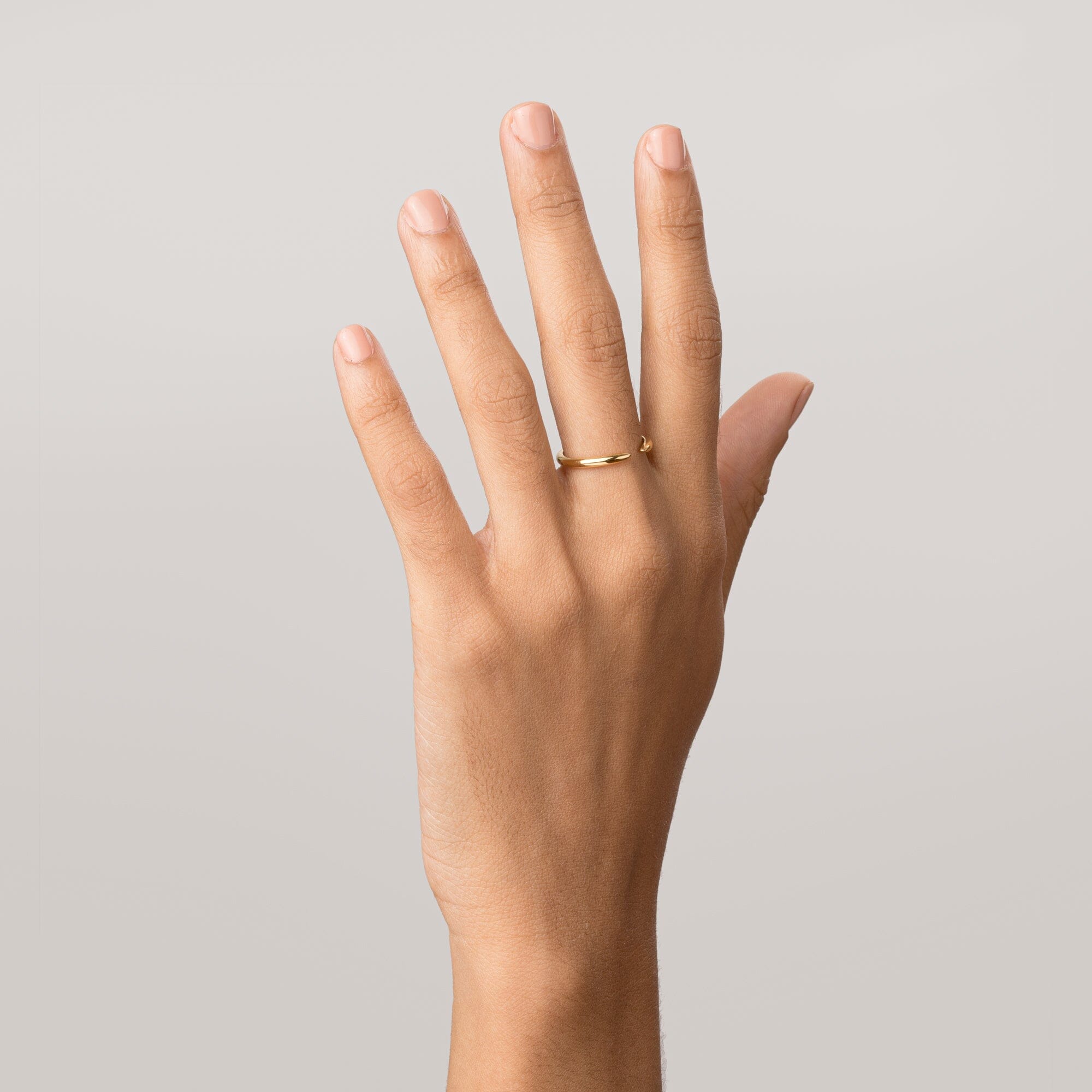Model hand wearing a thin gold ring