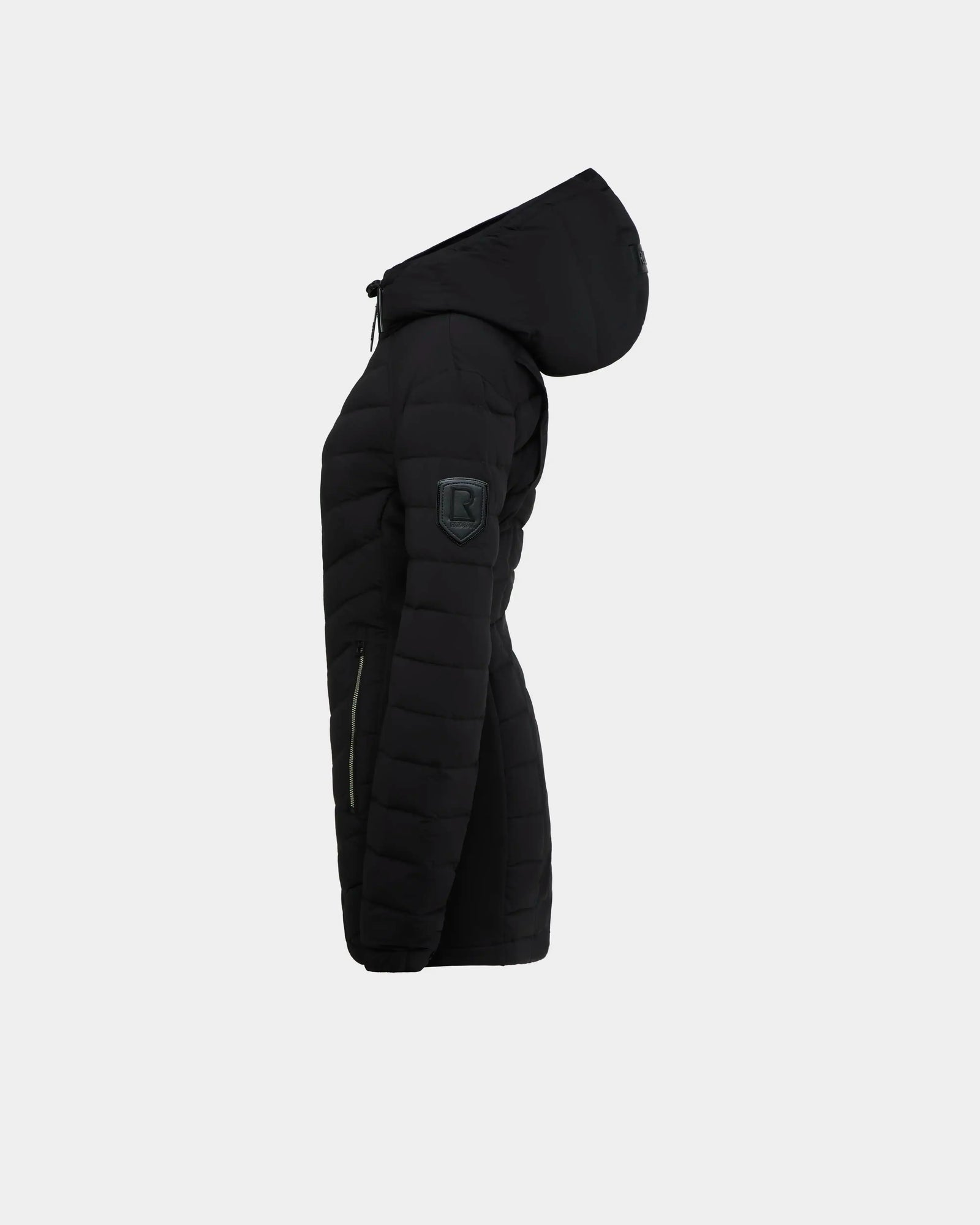 The Rudsak COSETTE - L124004 Black is a women’s fitted down jacket with a hood, matte fabric, zipper pocket, and patch logo on the upper sleeve. Shown side view against a plain light background.