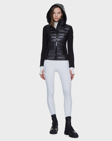 A woman faces forward wearing the Rudsak MABS - 8121012 BLACK lightweight activewear jacket with waterproof zippers, paired with white fitted pants and black combat boots against a plain white background.