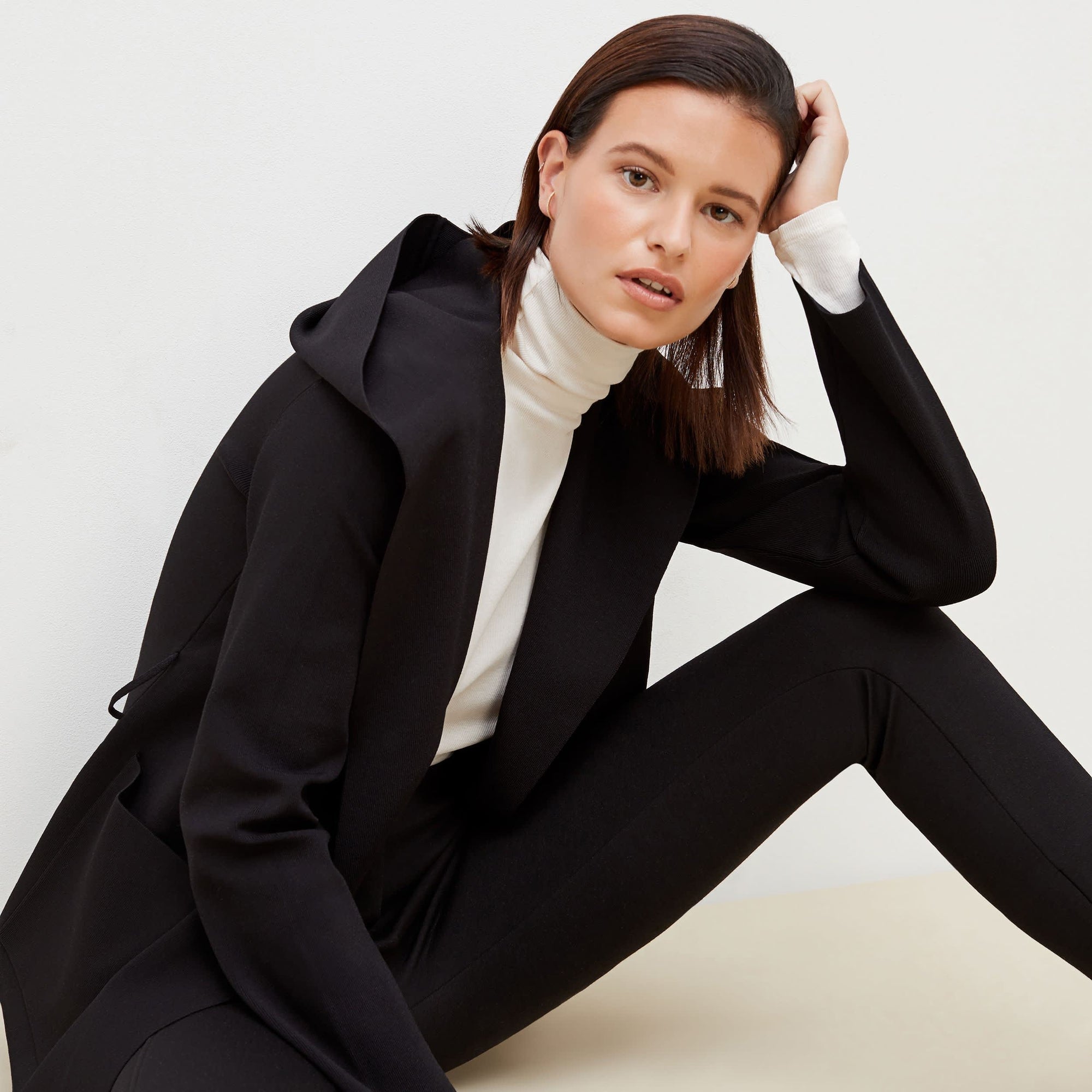 Side image of a woman sitting wearing the Curie Pant--Worth in Black | Exclude